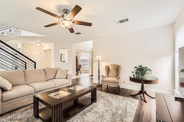 living area featuring visible vents, dark wood finished floors, baseboards, and stairs