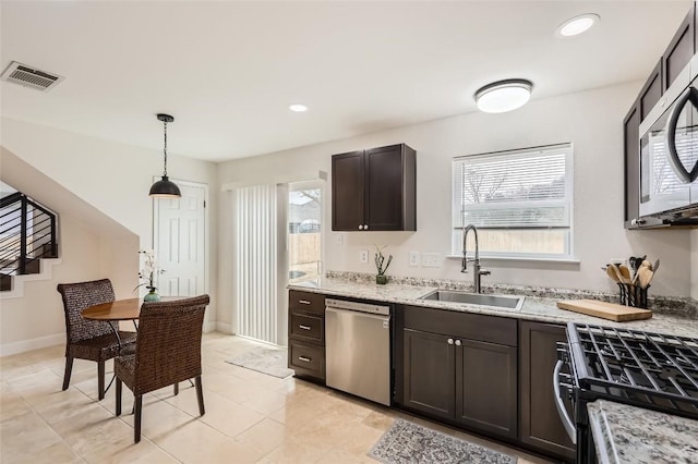 kitchen with dark brown cabinetry, stainless steel appliances, a sink, visible vents, and pendant lighting