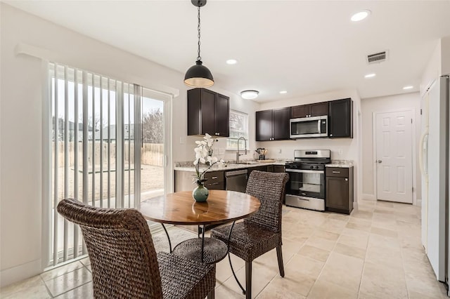 kitchen featuring light stone countertops, visible vents, pendant lighting, and stainless steel appliances