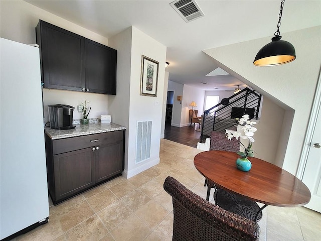 bar featuring visible vents, stairway, freestanding refrigerator, and decorative light fixtures