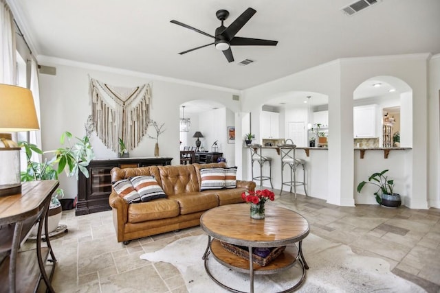 3304 Mulberry Creek Dr, Austin, TX 78732 - living room featuring ceiling fan, crown molding, light stone finish flooring, and arched walkways