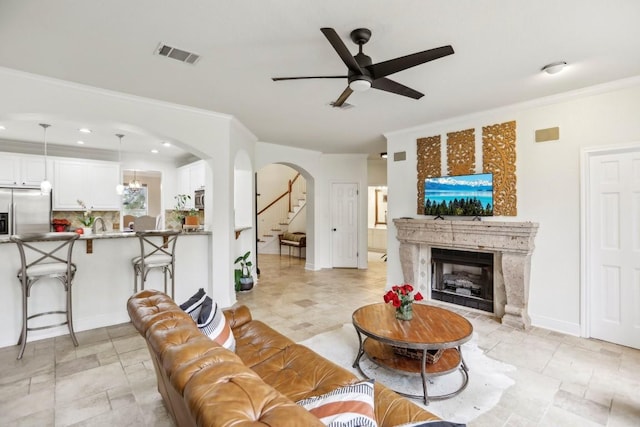 3304 Mulberry Creek Dr, Austin, TX 78732 - living room with ceiling fan, arched walkways, a fireplace, crown molding, and stairway