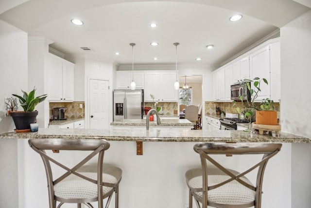 3304 Mulberry Creek Dr, Austin, TX 78732 - kitchen with appliances with stainless steel finishes, a peninsula, white cabinets, light stone countertops, and decorative light fixtures