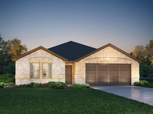 french country style house with a garage, concrete driveway, roof with shingles, and a yard