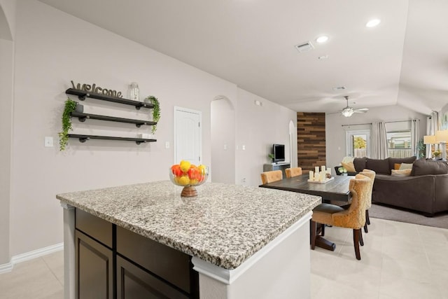 kitchen with visible vents, lofted ceiling, light stone counters, open floor plan, and open shelves