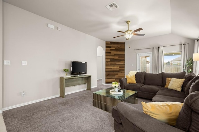 living room with carpet floors, arched walkways, visible vents, an accent wall, and wood walls