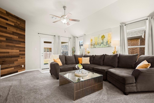 living room featuring dark colored carpet, visible vents, vaulted ceiling, wooden walls, and ceiling fan