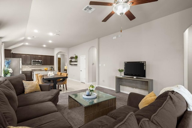 living area featuring arched walkways, visible vents, vaulted ceiling, and baseboards