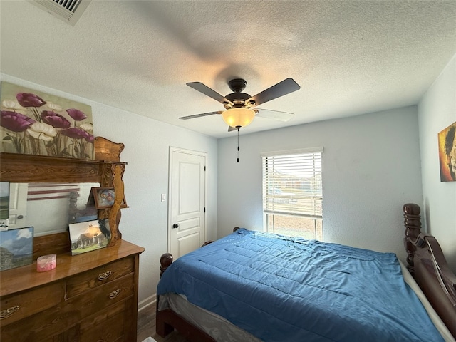 bedroom featuring ceiling fan, visible vents, and a textured ceiling