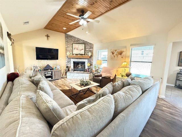 living room featuring lofted ceiling, a fireplace, visible vents, and wood finished floors