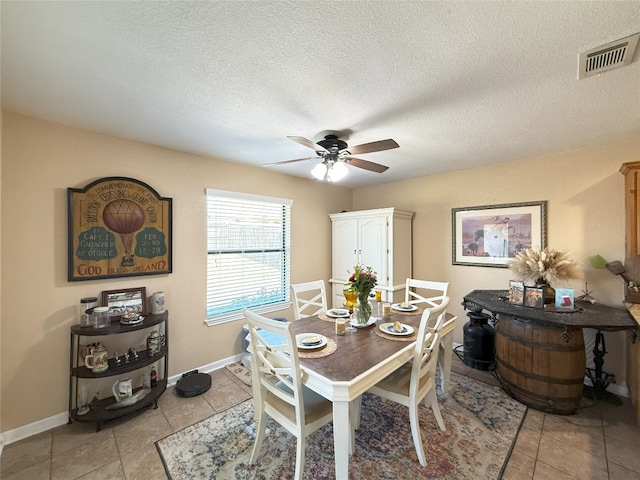 dining space with light tile patterned floors, baseboards, visible vents, and ceiling fan