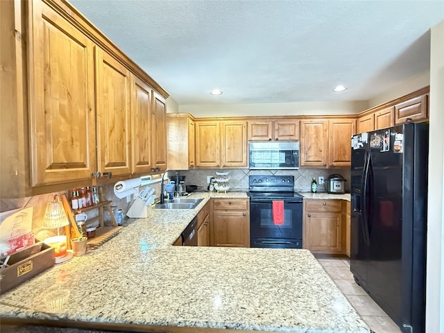 kitchen with brown cabinets, decorative backsplash, a sink, a peninsula, and black appliances