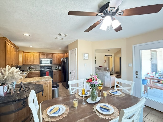 dining area with light tile patterned floors, visible vents, and a textured ceiling