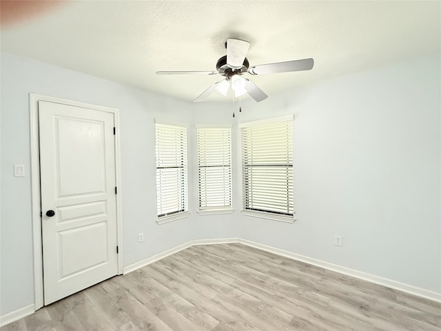 unfurnished room with a ceiling fan, baseboards, and light wood-style flooring