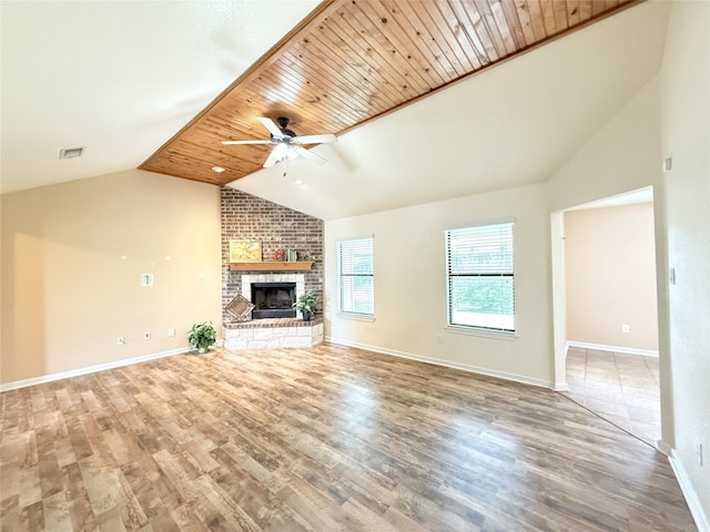unfurnished living room with visible vents, a fireplace, a ceiling fan, wood finished floors, and vaulted ceiling