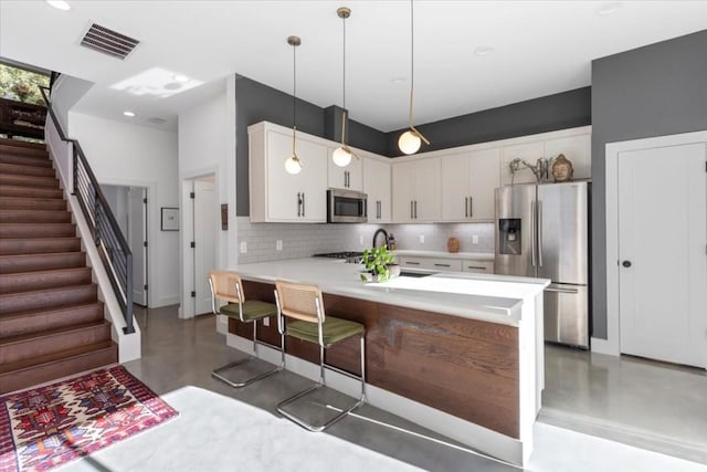 2115 Uphill Ln Unit A, Austin, TX 78741 - kitchen with finished concrete flooring, appliances with stainless steel finishes, visible vents, a peninsula, and backsplash