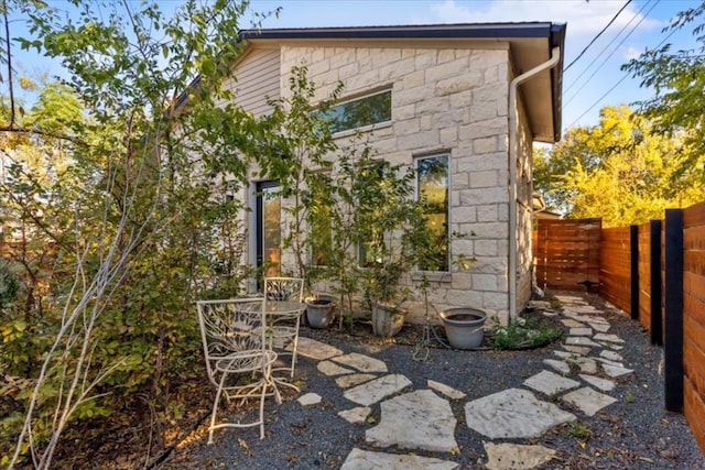 2115 Uphill Ln Unit A, Austin, TX 78741 - view of side of home featuring a fenced backyard, a patio area, and stone siding