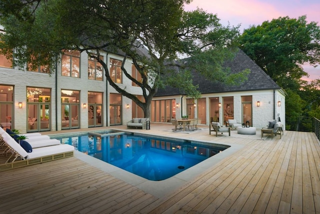outdoor pool featuring an outdoor hangout area, a deck, and french doors