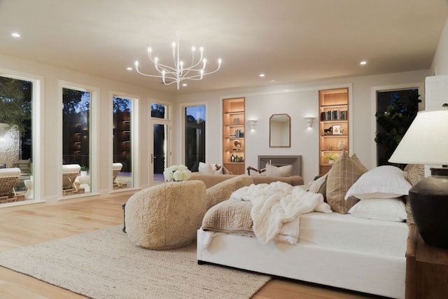 living area featuring recessed lighting, built in features, wood finished floors, and a notable chandelier