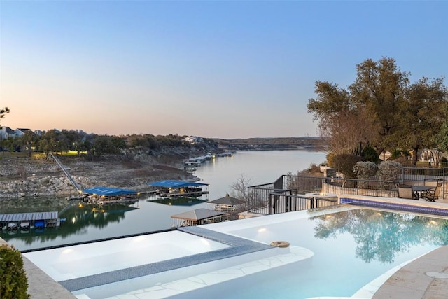 view of swimming pool with a water view and fence