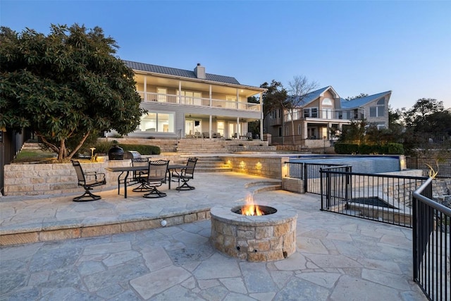 view of patio / terrace featuring fence, a fire pit, and an outdoor pool