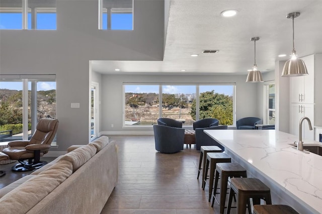 kitchen featuring open floor plan, a breakfast bar area, decorative light fixtures, and light stone countertops