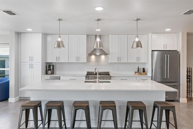 kitchen with a center island with sink, high end fridge, visible vents, white cabinets, and a sink