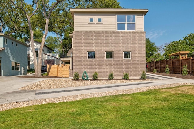 view of side of property with fence, a lawn, and brick siding