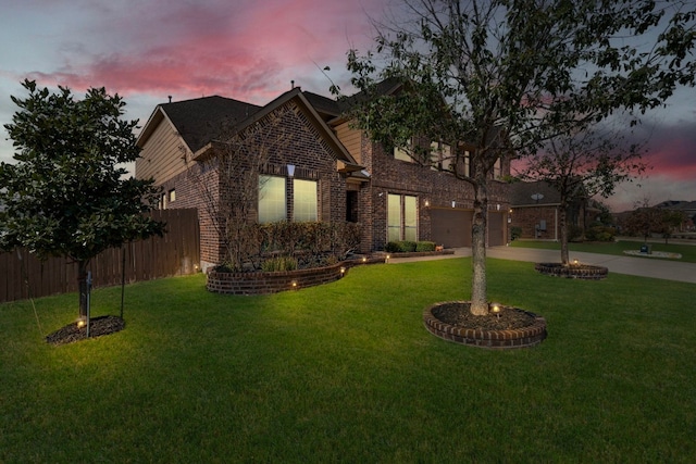 traditional home featuring driveway, a garage, a lawn, fence, and brick siding