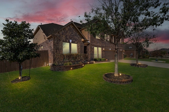 traditional-style home featuring a garage, fence, concrete driveway, a front yard, and brick siding