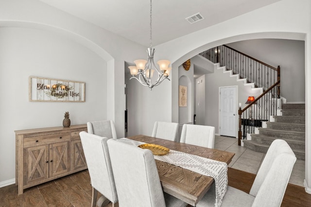 19900 Kite Wing Ter, Pflugerville, TX 78660 - dining space with arched walkways, a chandelier, stairs, dark wood-style flooring, and baseboards