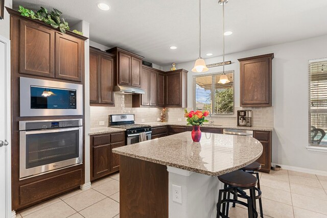 19900 Kite Wing Ter, Pflugerville, TX 78660 - kitchen featuring stainless steel appliances, under cabinet range hood, light tile patterned floors, decorative backsplash, and recessed lighting