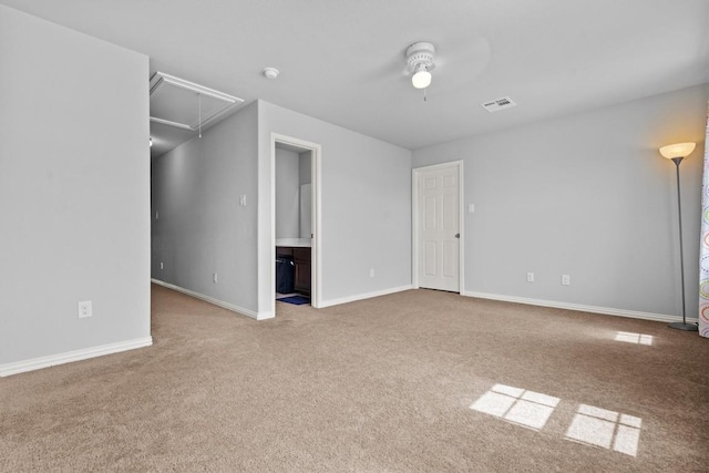 carpeted empty room featuring attic access, baseboards, a ceiling fan, and visible vents