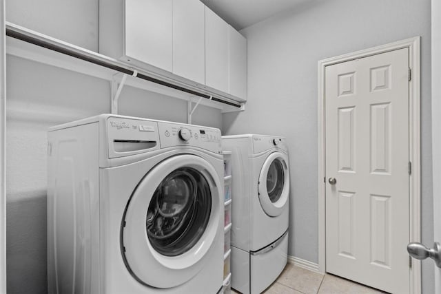 laundry room featuring washing machine and clothes dryer, light tile patterned flooring, and cabinet space