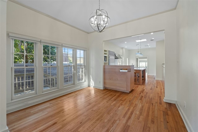 unfurnished dining area with baseboards, ornamental molding, light wood-type flooring, a chandelier, and recessed lighting