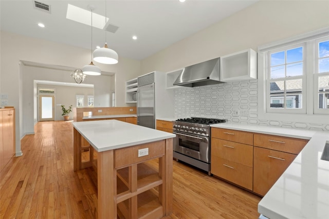 kitchen featuring premium appliances, visible vents, hanging light fixtures, light countertops, and wall chimney exhaust hood