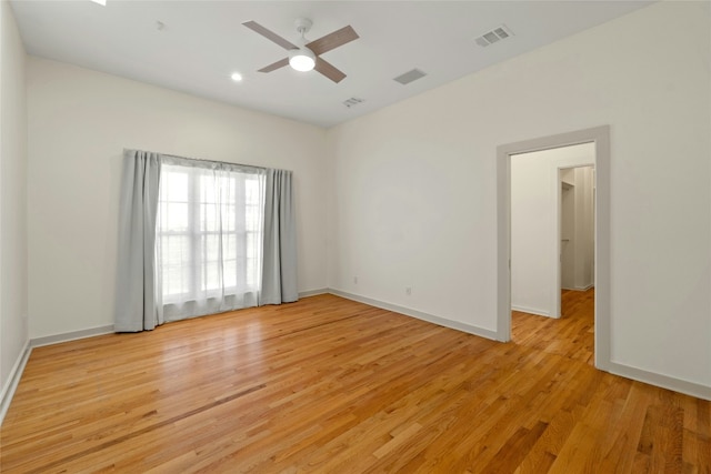 spare room featuring light wood-style flooring, a ceiling fan, visible vents, and baseboards