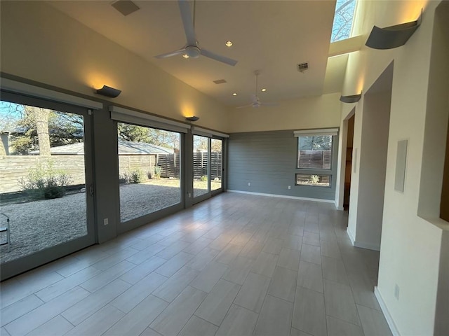 unfurnished sunroom with plenty of natural light, visible vents, and a ceiling fan