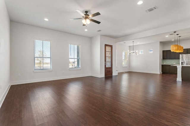 unfurnished living room featuring visible vents, dark wood finished floors, baseboards, and ceiling fan with notable chandelier