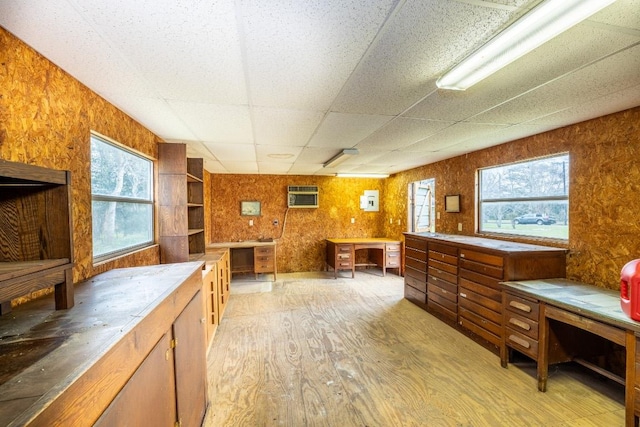 interior space featuring a wall unit AC, wood finished floors, a paneled ceiling, and wooden walls