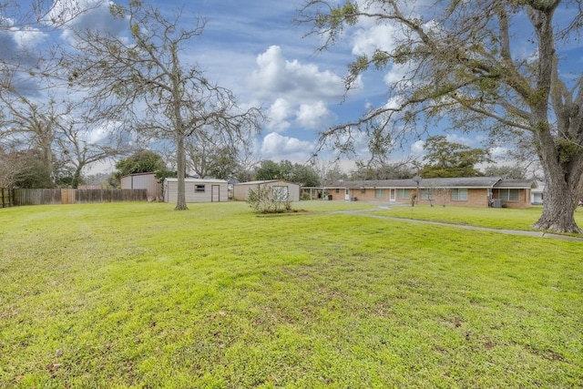 view of yard featuring an outbuilding, a storage unit, and fence