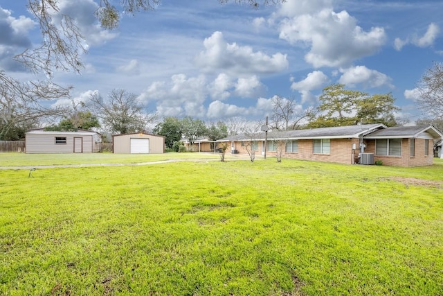 view of yard with a detached garage, central AC unit, and an outbuilding