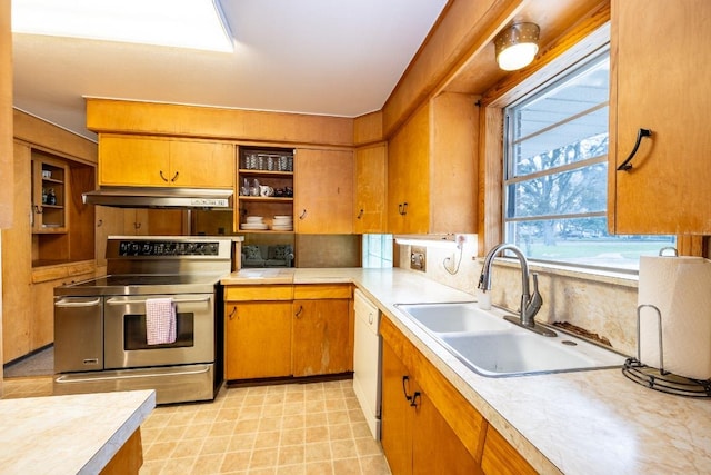 kitchen with a sink, under cabinet range hood, range with two ovens, and light countertops