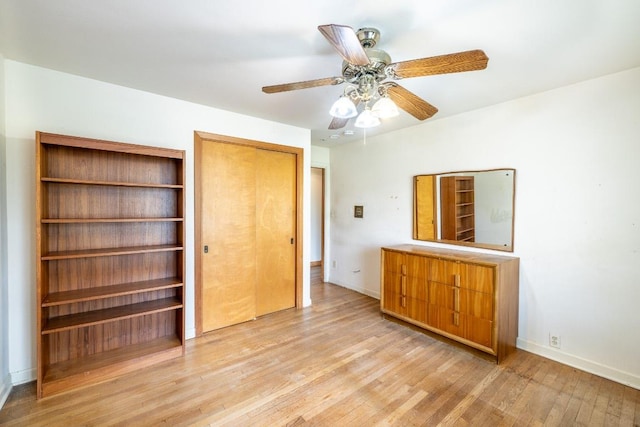 unfurnished bedroom featuring baseboards, a closet, a ceiling fan, and light wood-style floors