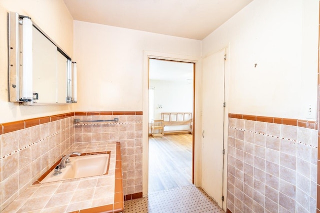 bathroom featuring a wainscoted wall and tile walls