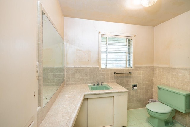 bathroom with tile patterned flooring, toilet, a wainscoted wall, vanity, and tile walls