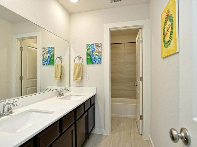 full bath with double vanity, baseboards, visible vents, and a sink