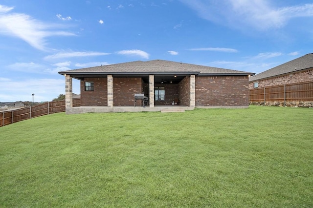 back of house with a fenced backyard, a patio, a lawn, and brick siding