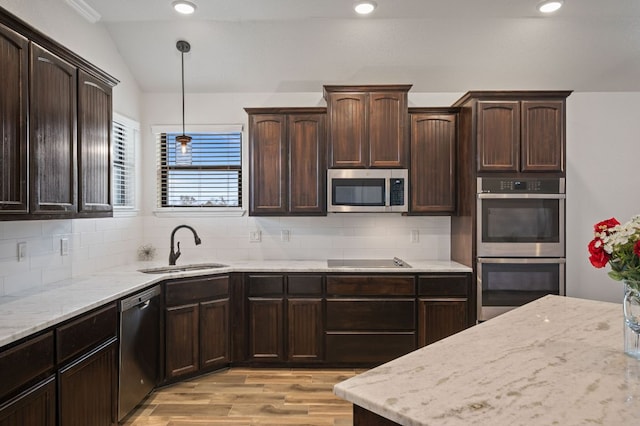 kitchen with stainless steel appliances, a sink, vaulted ceiling, tasteful backsplash, and pendant lighting