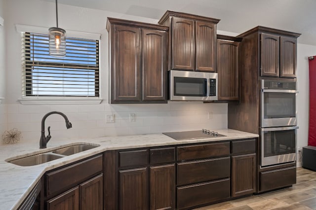 kitchen with a sink, hanging light fixtures, dark brown cabinets, decorative backsplash, and black appliances